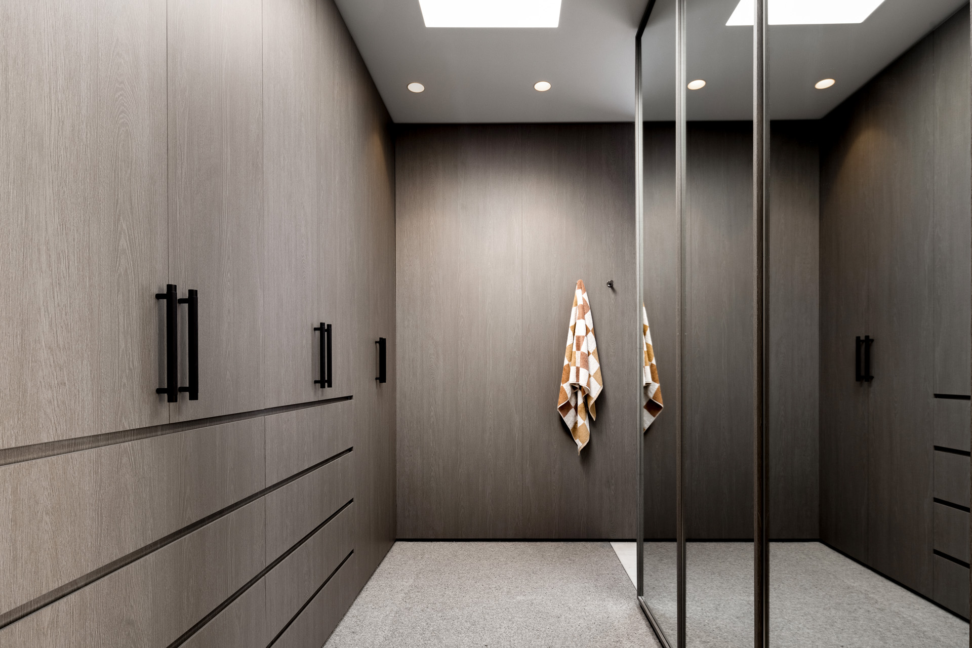 Master Walk in Robe featuring dark joinery and a mirror sliding wardrobe