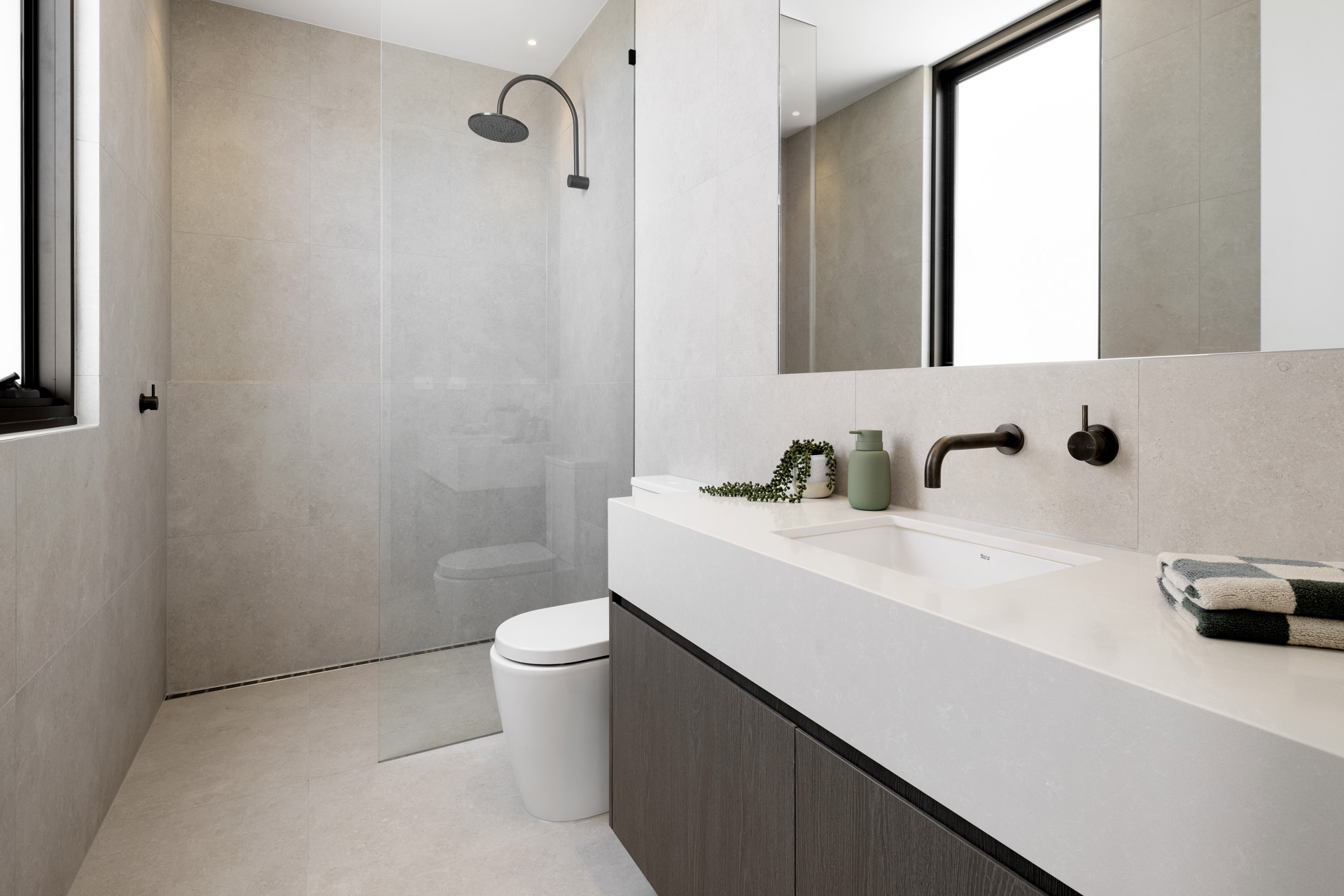An image of the ensuite featuring built in basin and cabinetry with a large rectangular wall mirror